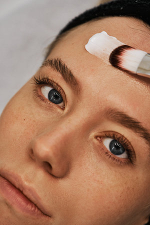 A smear of cream on the face of a young woman. Brush massage.の写真素材