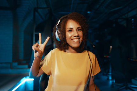 Young dark-skinned woman in headphones greeting people via webcam.の写真素材