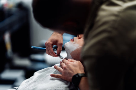 A barber shaves a man with a dangerous razor.の写真素材