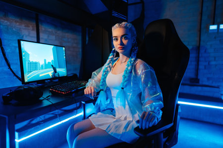 Young female blogger, gamer plays games on computer. Neon computer club.の写真素材