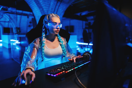 Young female blogger, gamer plays games on computer. Neon computer club.の写真素材