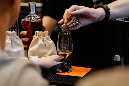 The bartender pours whiskey into a tasting glass for a sample.の写真素材