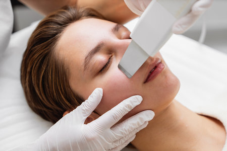 Female receiving a facial treatment with a handheld device in a spa during the dayの写真素材