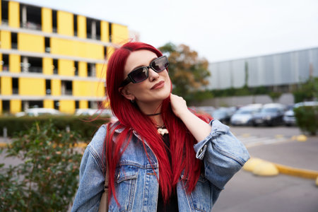 Young woman with red hair poses confidently in urban setting during daytime