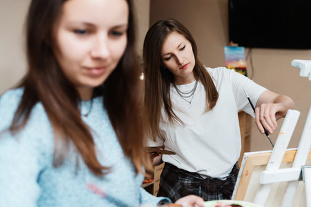 Two artists enjoying a creative painting session in a cozy studio spaceの写真素材
