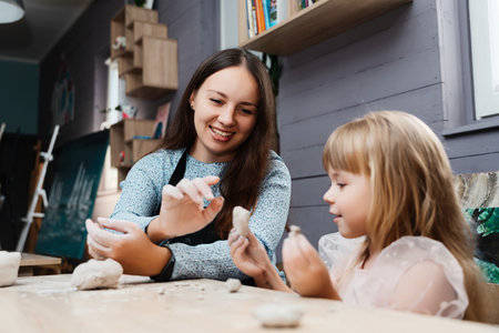 Girl and her mother enjoying a fun clay modeling activity indoors