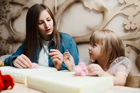 A mother and daughter enjoy crafting together in a cozy workshop settingの写真素材