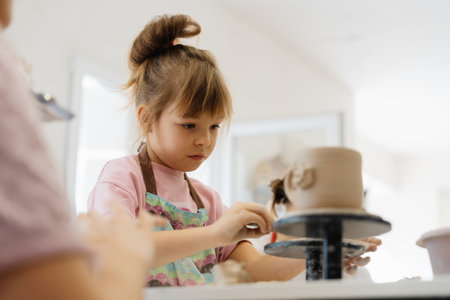 Girl creating pottery in a bright, cheerful workshop settingの写真素材