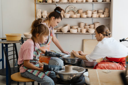 Children and adults creating pottery together in a bright studioの写真素材