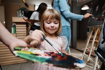 Girl joyfully painting at an art class with peers in a creative spaceの写真素材