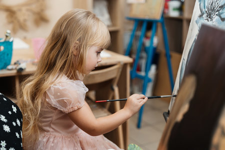Child painting on an easel in a creative art classroom settingの写真素材
