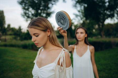 Two women in a garden during daytime with one holding a unique objectの写真素材