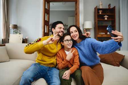 Family enjoying a cozy indoor moment while taking a selfie togetherの写真素材