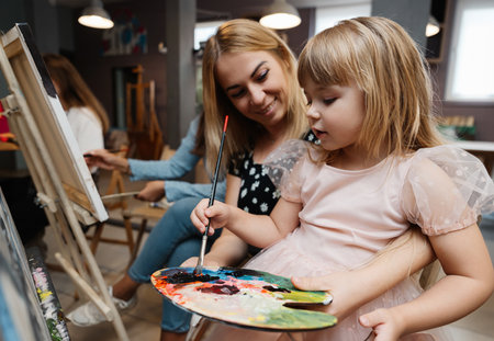 A mother and daughter enjoying a creative painting session at an art studioの写真素材