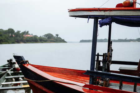 Fishing boats moored by the tranquil waters of a river on a cloudy day