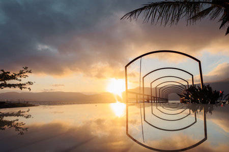 Serene sunset view over a reflective pool in a tropical landscapeの写真素材
