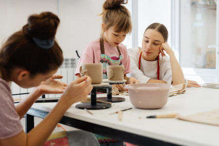 A mother and daughter enjoy pottery making together in a sunny studioの写真素材