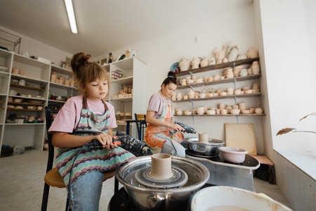 Girl and her mother create pottery in a bright studioの写真素材