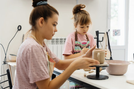 A mother and daughter creating pottery together at a sunny studio