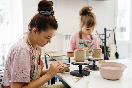 Artists create ceramic pots together in a studio on a sunny afternoon