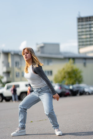Young woman performs dance moves in urban setting on sunny dayの写真素材