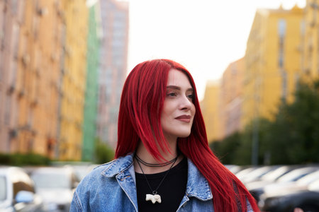 Young woman with vibrant red hair walks through urban street in summer