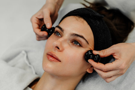 Woman receiving a facial treatment with massage tools in a serene settingの写真素材