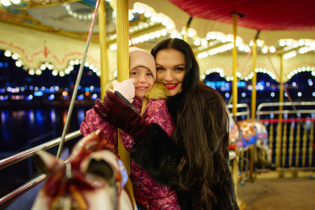 Family bonding at night on a carousel with city lights in the backgroundの写真素材