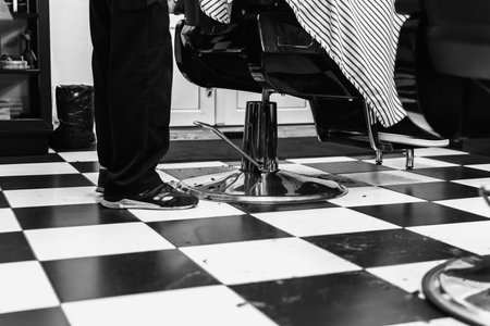 Haircut in a modern barbershop with classic black and white checkerboard floorの写真素材