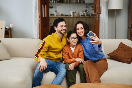 Family enjoying quality time while taking a selfie on a cozy sofa at homeの写真素材