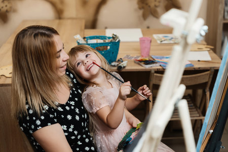 Mother and daughter sharing a joyful painting moment in an art studioの写真素材