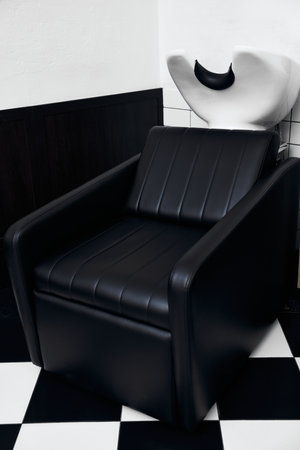 Stylish black salon chair positioned next to a unique hair washing stationの写真素材