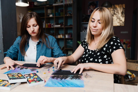 Two women creating pastel artwork together in a cozy studio settingの写真素材