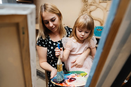 A mother and daughter painting together in a cozy home environmentの写真素材
