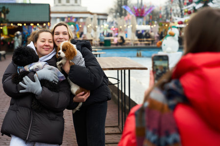 Group of friends enjoying a winter day with dogs at an outdoor festival in a festive settingの写真素材