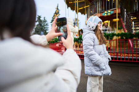 Friends capturing memories at a festive fairground during winterの写真素材