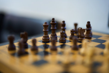 Chess pieces positioned on a wooden board during a competitive matchの写真素材