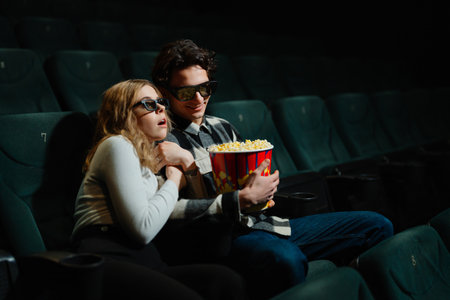 Young couple enjoying popcorn at the movies during a thrilling momentの写真素材
