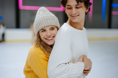 Couple enjoys ice skating together at a rink during winter afternoonの写真素材