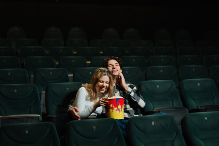 Couple enjoying popcorn together in an empty movie theaterの写真素材