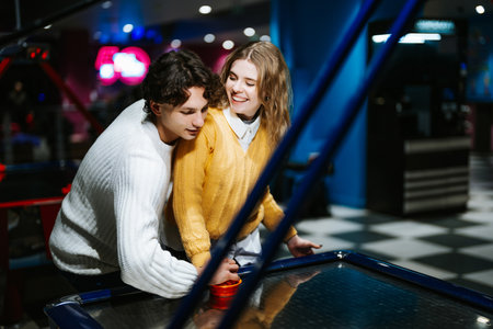Young couple enjoys air hockey at an arcade during a fun evening together