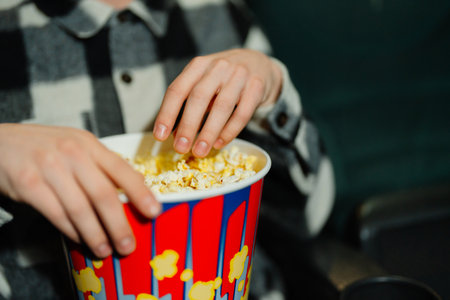 Enjoying popcorn during a movie theater experience at night with friendsの写真素材