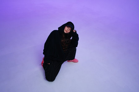 Young woman in casual streetwear poses on a colorful backdrop