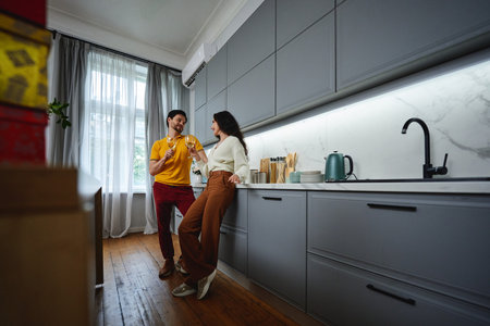 Couple enjoying a playful moment in a modern kitchen during daytimeの写真素材