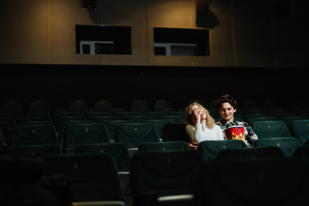 Couple enjoying a movie together in an almost empty theater at nightの写真素材