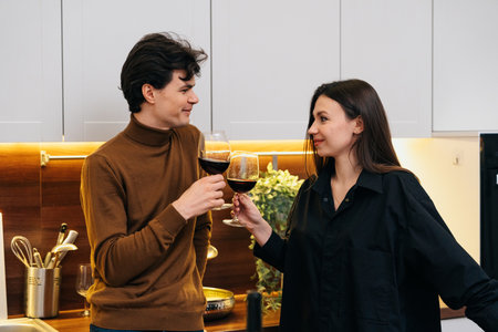 Couple enjoying a toast in a modern kitchen with warm lightingの写真素材