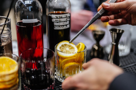 Crafting a refreshing cocktail with fresh lemon slices at a bar
