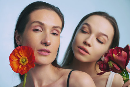 Two women posing with colorful flowers in a bright studio settingの写真素材