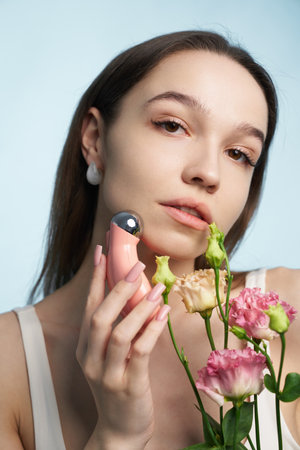 Woman holding beauty device and flowers with soft blue backgroundの写真素材