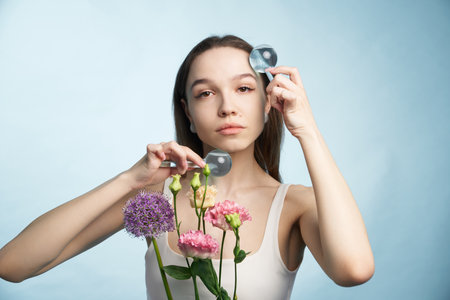 Woman holds flowers while using magnifying glasses for observationの写真素材